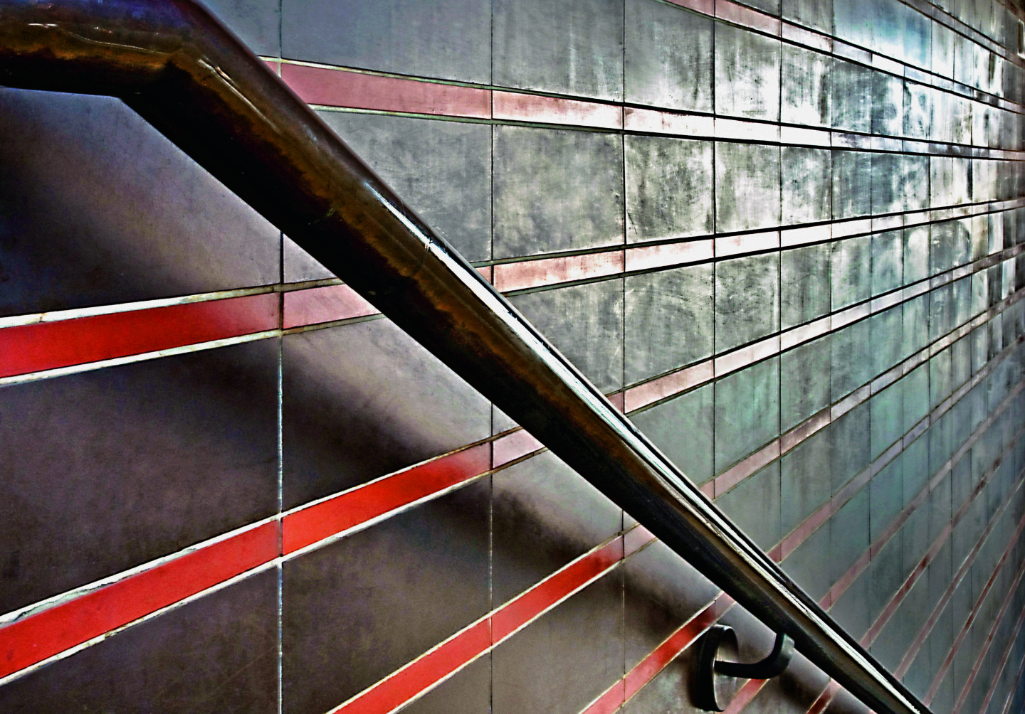 Handlauf aus Tombak, dahinter die rot-braunen Fliesenbänder, die sich durch die Gebäude der Tabakfabrik ziehen.